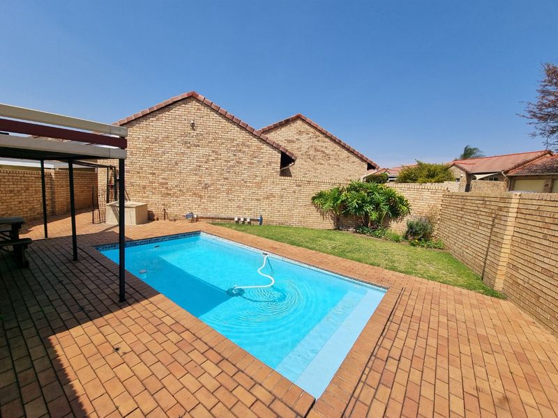 Private backyard featuring a swimming pool, brick paved patio area, and perimeter brick walling.