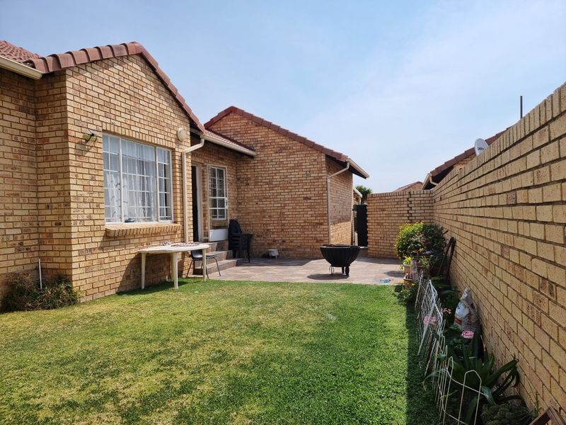 A private rear garden featuring a paved patio area, well-maintained lawn, and secure perimeter brick walling, ideal for outdoor relaxation.