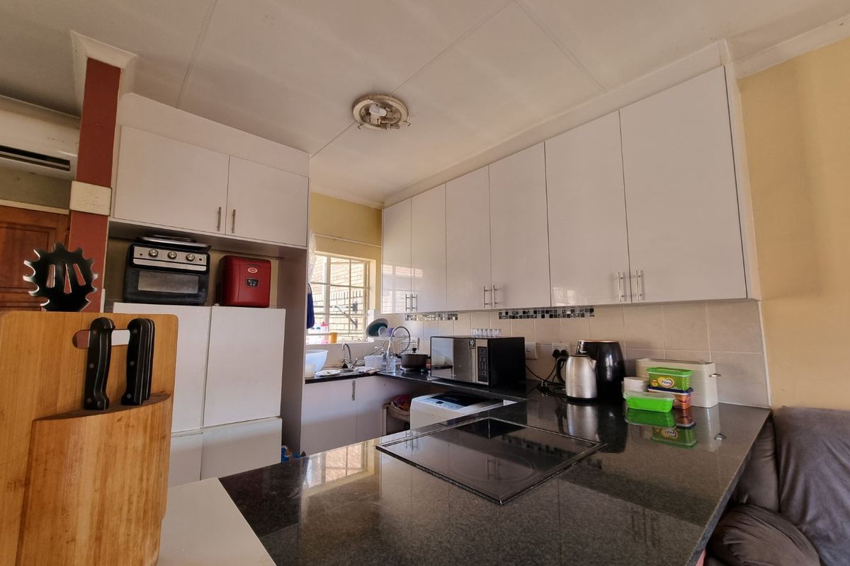 Functional kitchen featuring white cabinetry, dark granite countertops, integrated hob and oven, and a tiled backsplash with a practical layout.