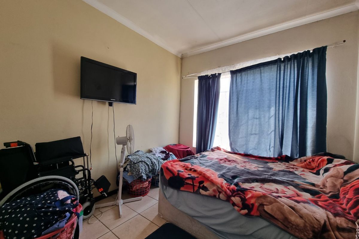 A bedroom featuring tiled flooring and a wall-mounted television bracket, requiring cosmetic updates to improve the overall aesthetic and condition.