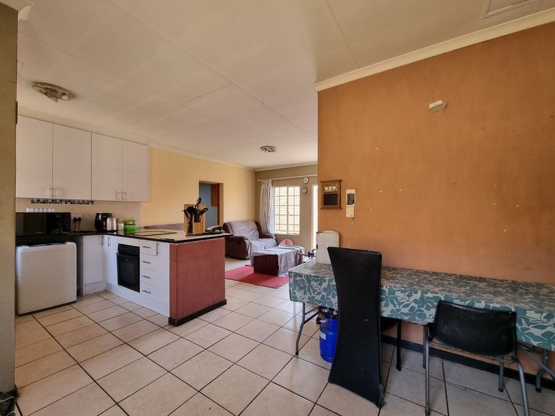Open-plan kitchen and living area featuring tiled flooring, built-in cabinetry, and an integrated oven, offering a functional layout with potential for modernization.