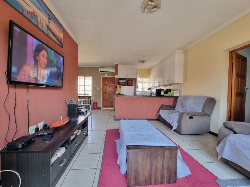 Open-plan living and kitchen area featuring tiled flooring, built-in cabinetry, and a breakfast counter, offering a functional layout for daily living.