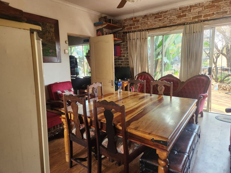 Dining room featuring an exposed brick feature wall, laminate flooring, and a sliding glass door providing access to the outdoor area.