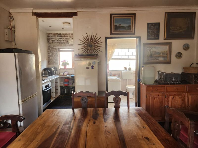 Open plan living and dining area featuring an adjacent kitchen with exposed brickwork and direct access to a secondary utility or bathroom space.