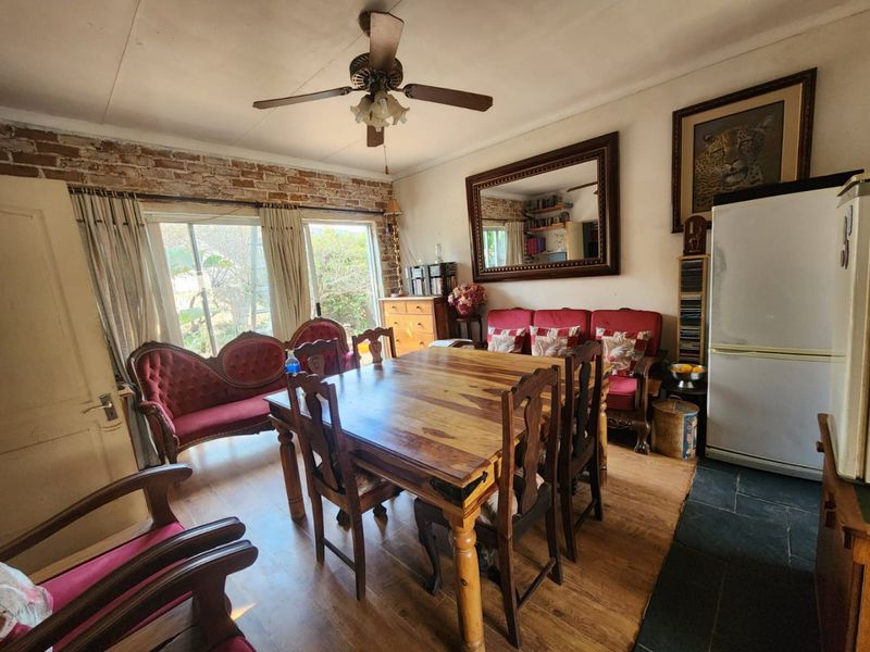 Dining area featuring exposed brick wall detailing, ceiling fan, and a combination of laminate and slate flooring.