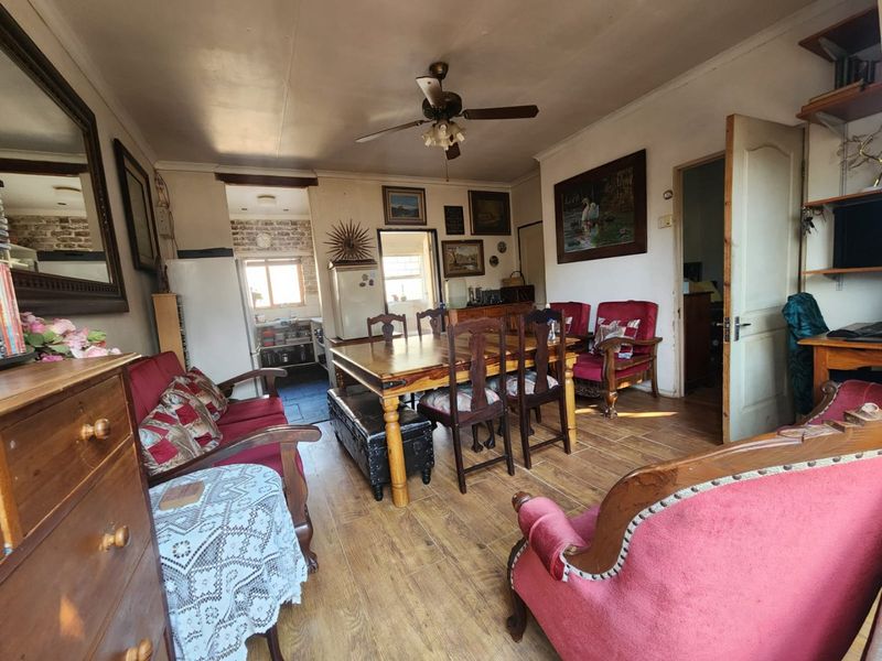 Open plan living and dining area featuring laminate flooring and a ceiling fan, with an adjacent kitchen visible in the background.