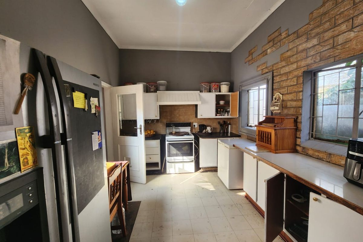 A dated kitchen featuring built-in cabinetry, a freestanding stove, and an exposed brick feature wall, requiring cosmetic updates to modernize the space.