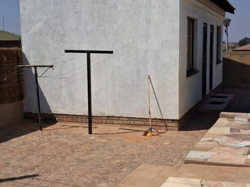 Rear exterior area featuring a paved patio, tiled steps, and a satellite dish mounted on the side wall.