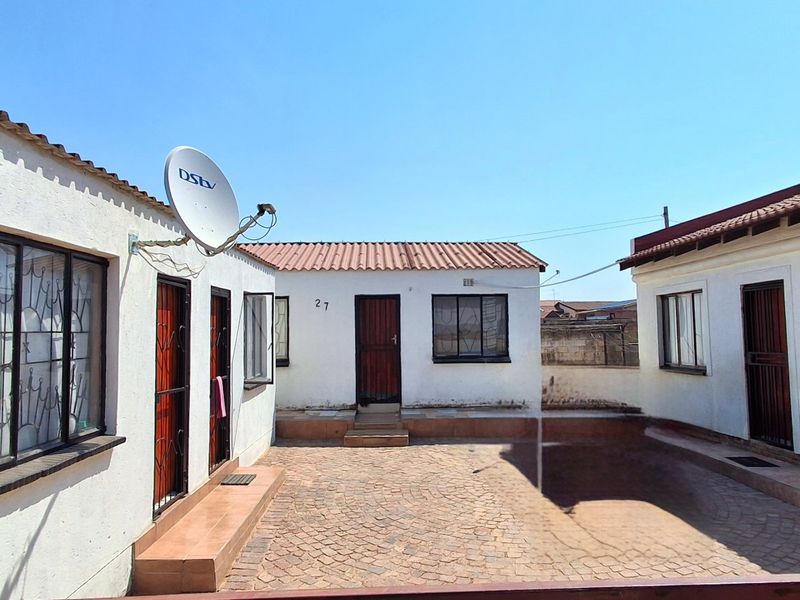 A paved rear courtyard area surrounded by multiple building sections with security gates and tiled roofing.