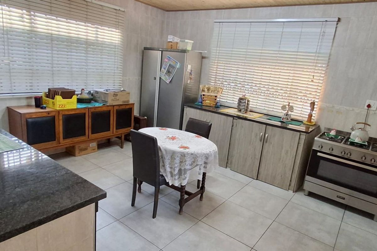 A functional kitchen featuring granite countertops, built-in oven with gas hob, tiled flooring, and ample cabinetry storage.