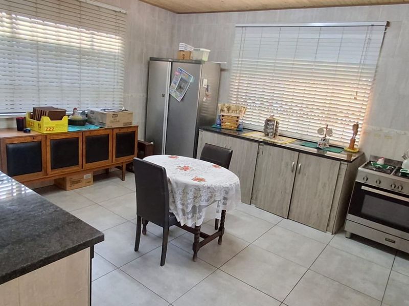 A functional kitchen featuring granite countertops, built-in oven with gas hob, tiled flooring, and ample cabinetry storage.