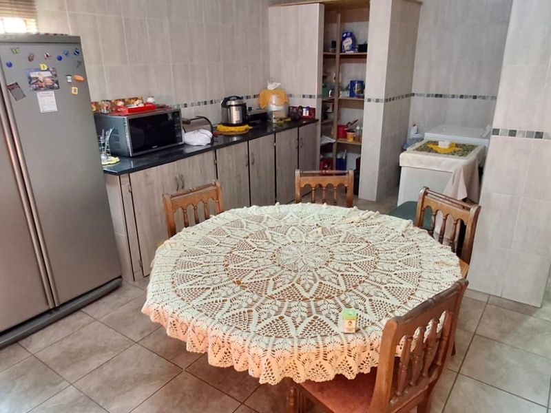 A functional kitchen featuring tiled walls and flooring, ample built-in cabinetry, and a dedicated pantry area, offering a practical layout for daily use.