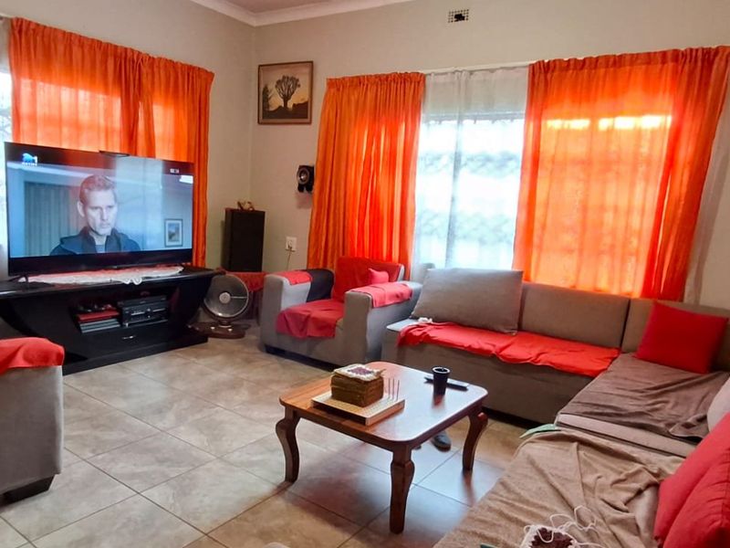 A living room featuring tiled flooring, cornicing, and windows fitted with security bars.