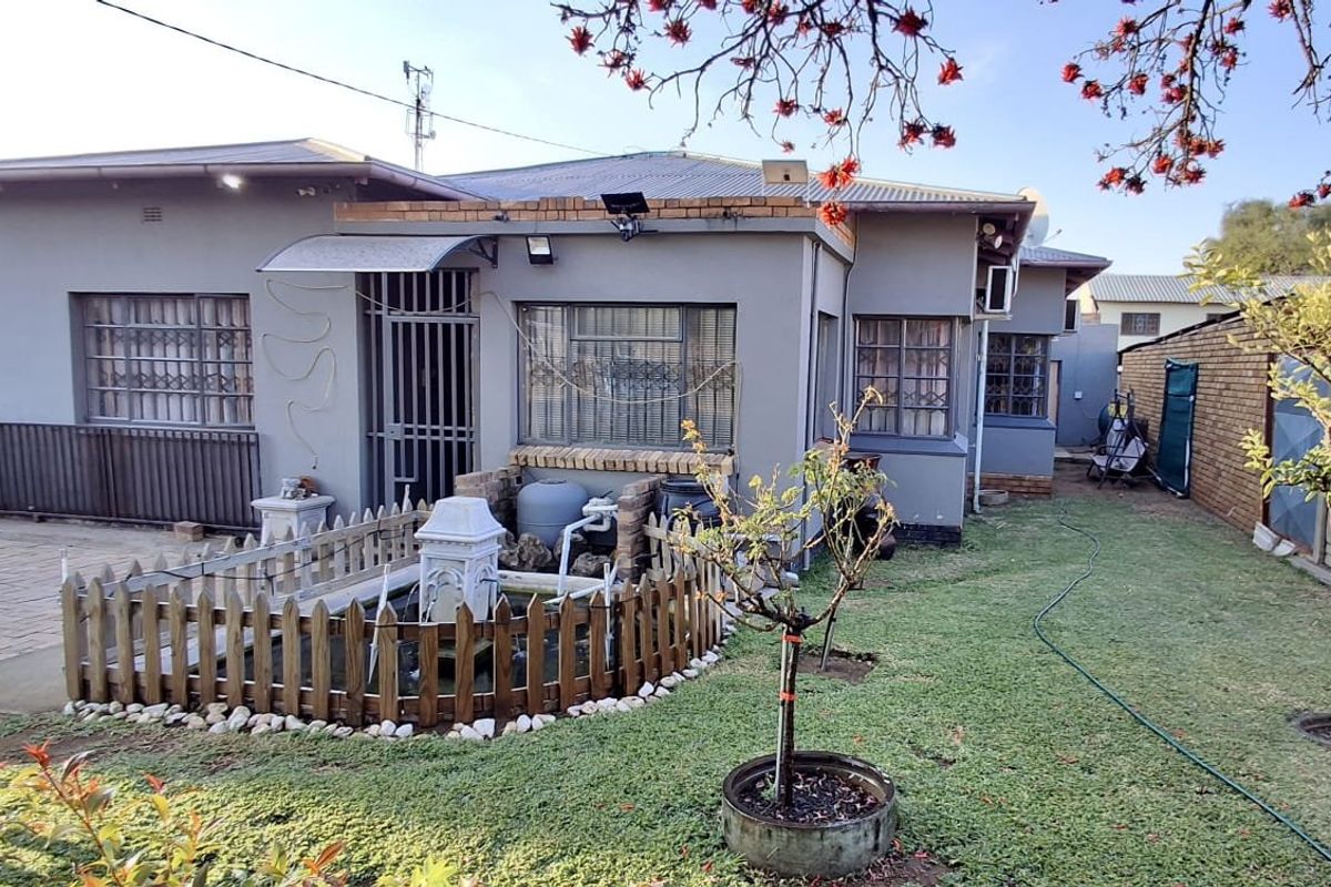 Rear view of the property featuring a paved area, a small water feature, and a garden space with established boundary walls.