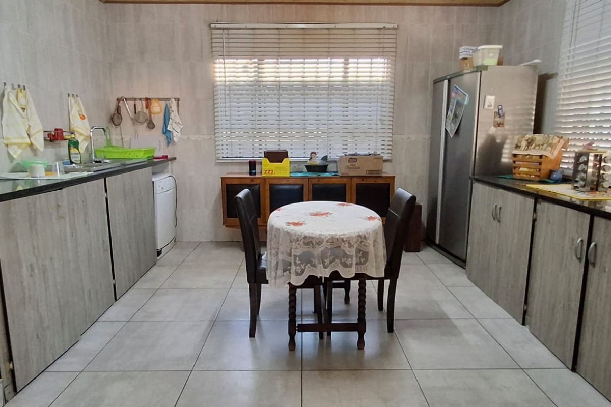 A functional kitchen featuring light wood-grain cabinetry, granite countertops, tiled walls, and tiled flooring, offering a practical layout with ample storage space.