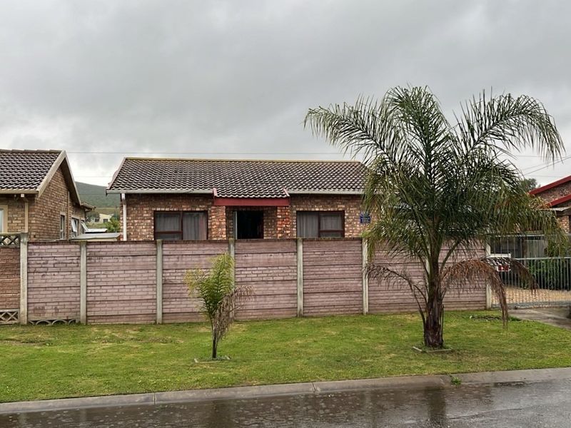 Front view of a face brick house featuring a tiled roof, aluminium window frames, and a precast concrete boundary wall.
