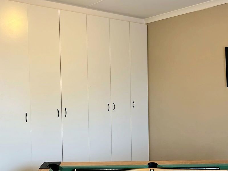 A bedroom featuring floor-to-ceiling built-in cupboards with white cabinetry and coved ceiling detailing.