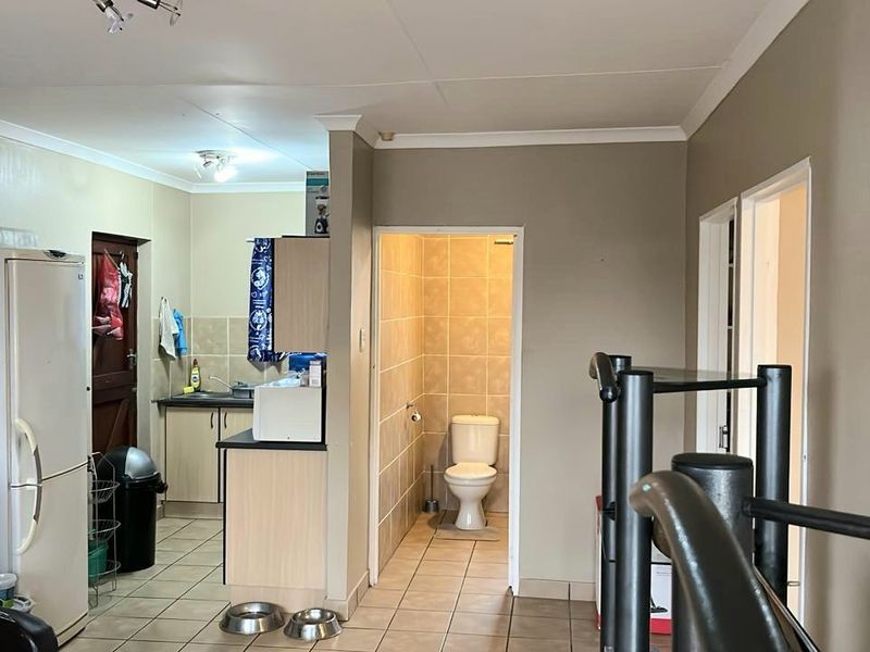 Open plan living area featuring a compact kitchen with built-in cabinetry and an adjacent tiled bathroom with a standard toilet.