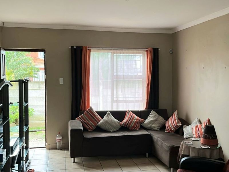A living room featuring tiled flooring, a sliding door providing outdoor access, and a window with security bars.
