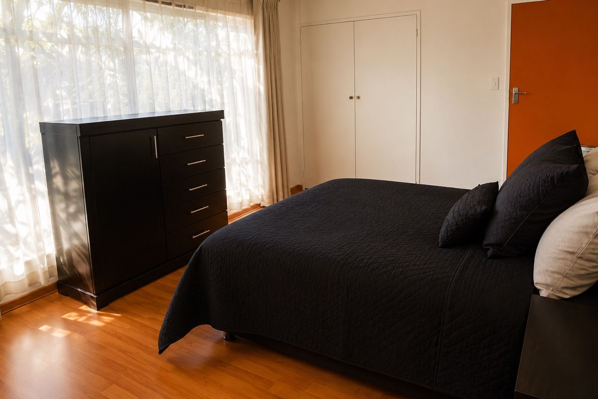 A bedroom featuring laminate flooring and a built-in wardrobe, offering a functional space with natural light.