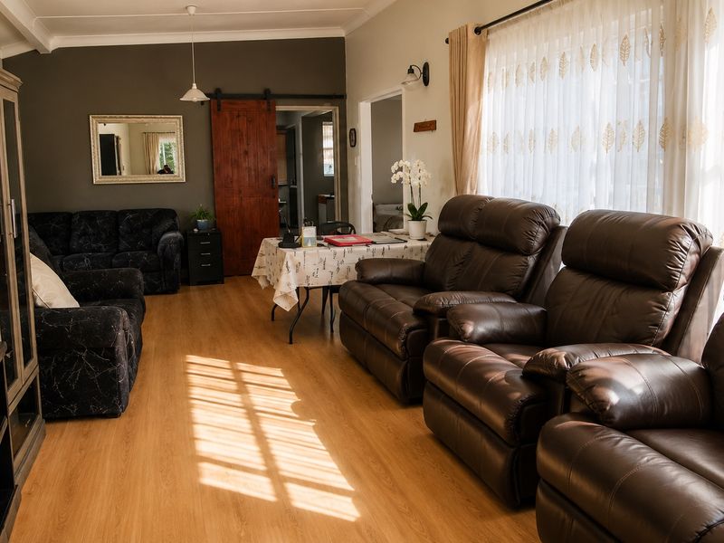 A spacious living room featuring laminate flooring, a sliding barn door, and natural light streaming through large windows.