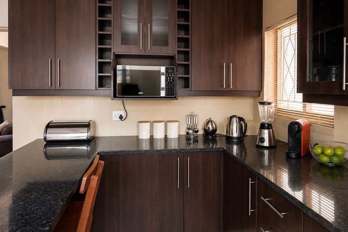 A well-maintained kitchen featuring dark wood cabinetry, granite countertops, and a built-in microwave, offering a functional and modern workspace.