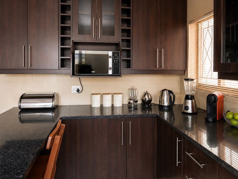 A well-maintained kitchen featuring dark wood cabinetry, granite countertops, and a built-in microwave, offering a functional and modern workspace.