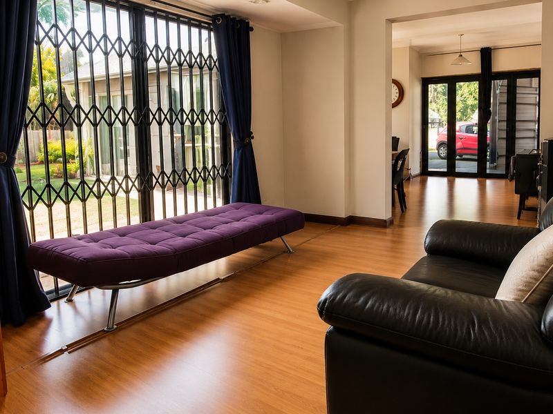A bright living room featuring laminate flooring and a large sliding glass door with a security gate, providing access to the outdoor area.