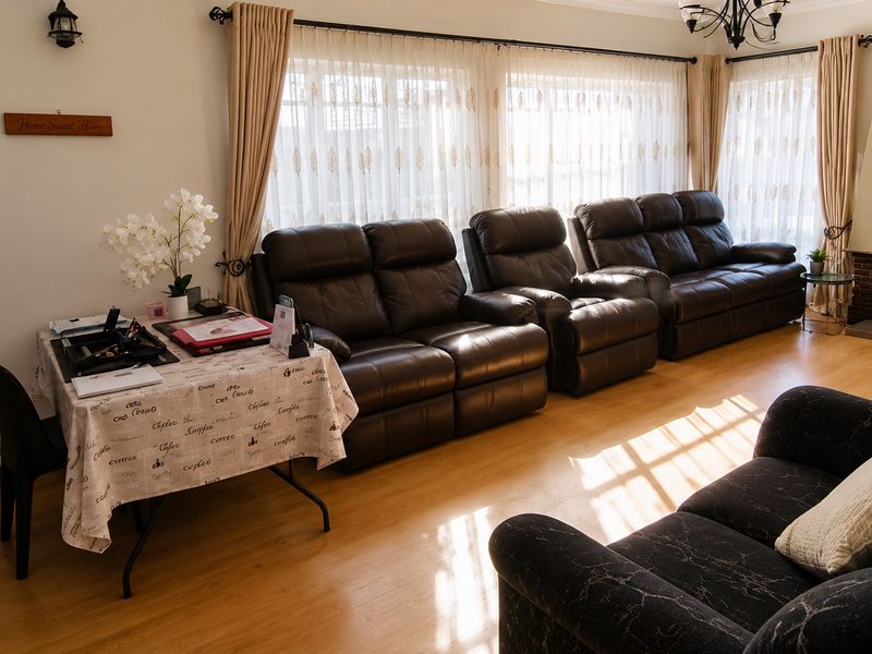 A spacious living room featuring laminate flooring and a brick fireplace, offering a comfortable and functional layout with ample natural light.