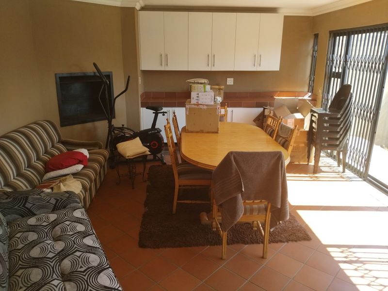 Open plan living and dining area featuring built-in cabinetry, tiled flooring, and a fireplace with access to an outdoor area via a security gate.