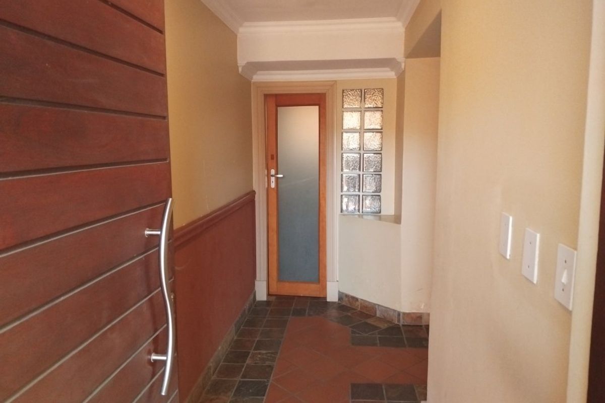 An entrance hall featuring a timber front door, tiled flooring, a decorative glass block feature, and a dado rail along the wall.