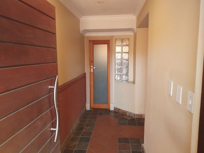 An entrance hall featuring a timber front door, tiled flooring, a decorative glass block feature, and a dado rail along the wall.