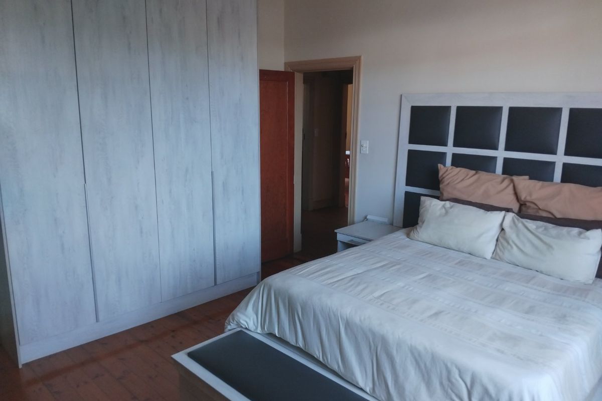 A well-maintained bedroom featuring timber flooring and floor-to-ceiling built-in cupboards, offering a clean and functional living space.