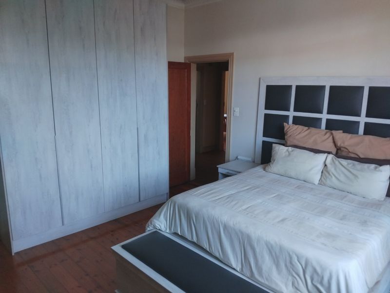 A well-maintained bedroom featuring timber flooring and floor-to-ceiling built-in cupboards, offering a clean and functional living space.