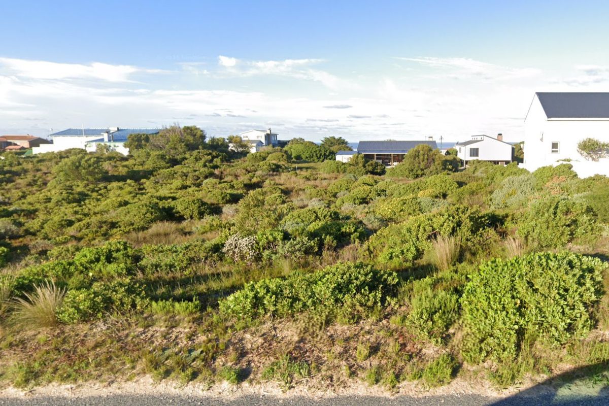 A vacant residential plot covered in natural coastal vegetation, offering a blank canvas for future development in a quiet neighborhood.