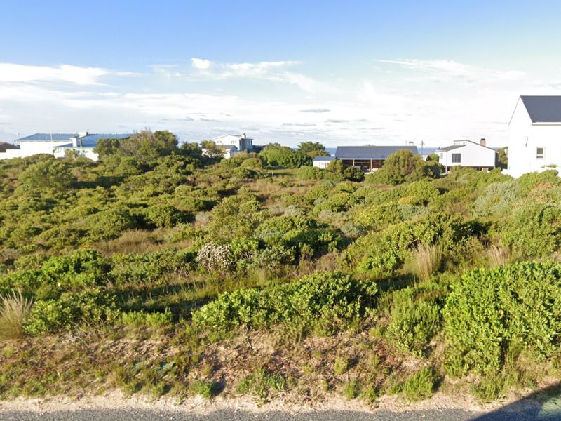 A vacant residential plot covered in natural coastal vegetation, offering a blank canvas for future development in a quiet neighborhood.