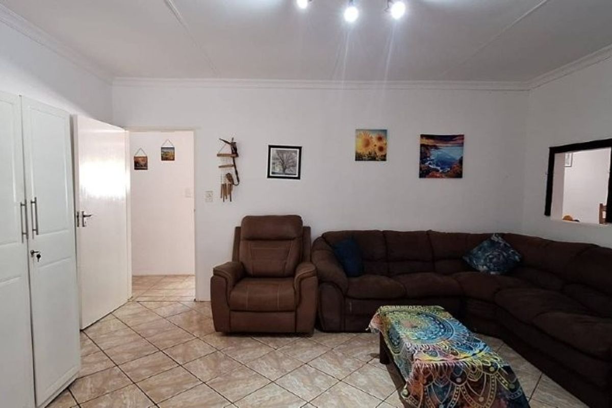 A living room featuring ceramic tiled flooring, built-in storage cupboards, and cove cornicing, providing a functional and neutral living space.