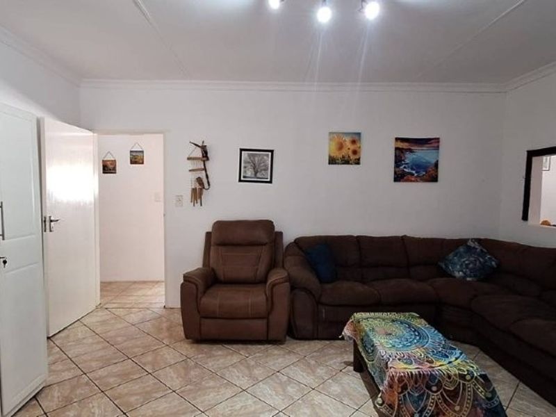 A living room featuring ceramic tiled flooring, built-in storage cupboards, and cove cornicing, providing a functional and neutral living space.