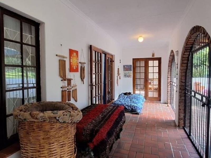 A covered patio area featuring terracotta tile flooring, arched brick architectural details, and multiple sets of french doors providing access to the home.