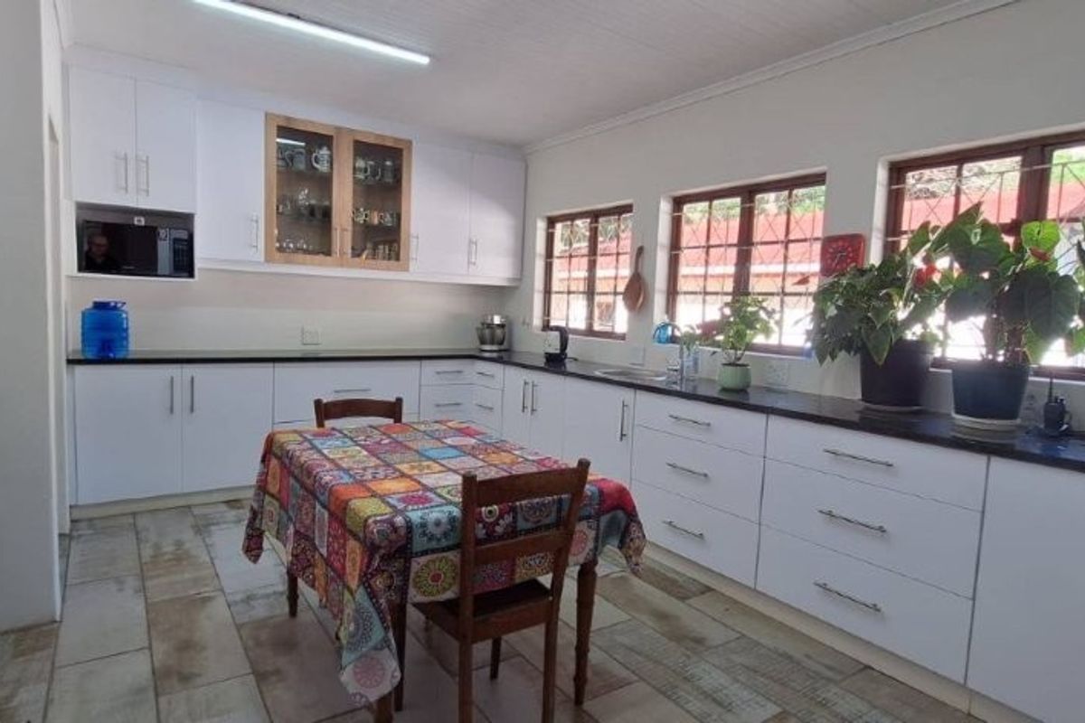 A bright, functional kitchen featuring white cabinetry, dark countertops, and tiled flooring, offering ample storage and workspace with natural light from multiple windows.