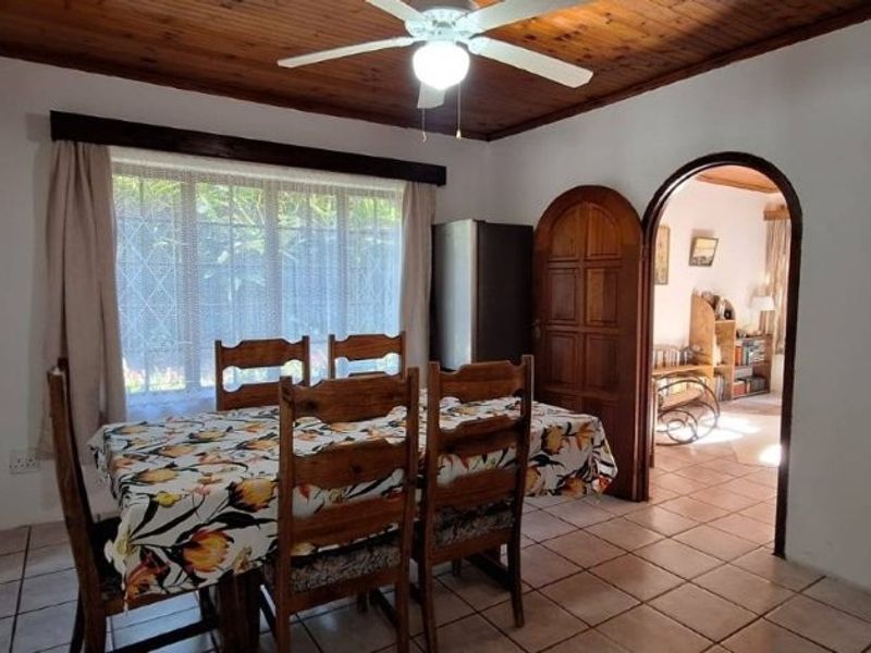 Dining room featuring a timber ceiling with a central fan, tiled flooring, and an arched doorway leading to an adjacent living space.