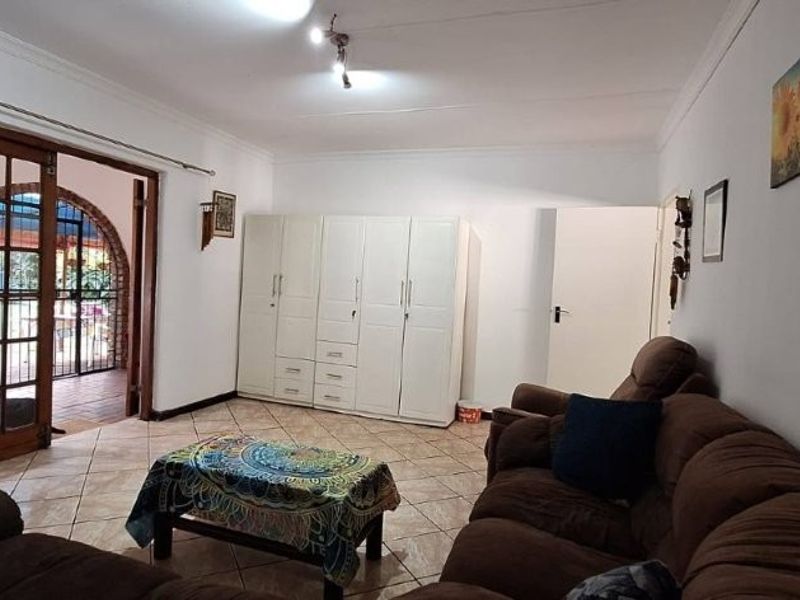A living room featuring tiled flooring, a built-in wardrobe, and a sliding glass door providing access to an outdoor patio area.