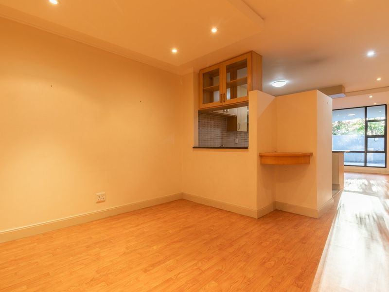An open-plan living area featuring laminate flooring, recessed lighting, and a convenient pass-through window connecting to the kitchen space.