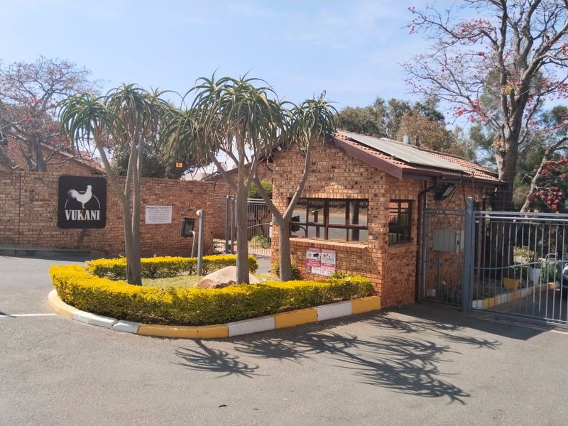 The entrance to the Vukani complex features a brick security guard house, perimeter walling, and secure metal gate access.