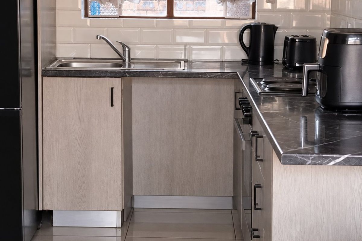 A modern, well-maintained kitchen featuring light wood-finish cabinetry, dark stone-look countertops, subway tile backsplash, and integrated cooking appliances.