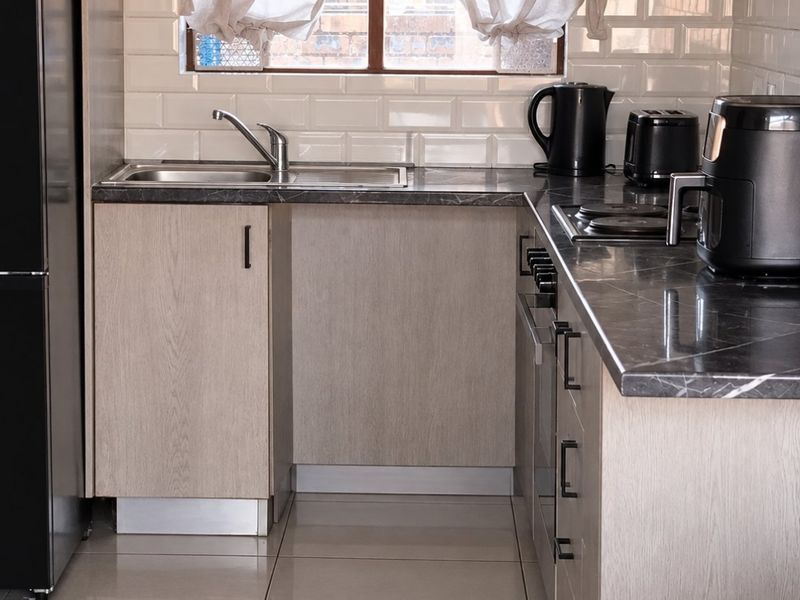A modern, well-maintained kitchen featuring light wood-finish cabinetry, dark stone-look countertops, subway tile backsplash, and integrated cooking appliances.