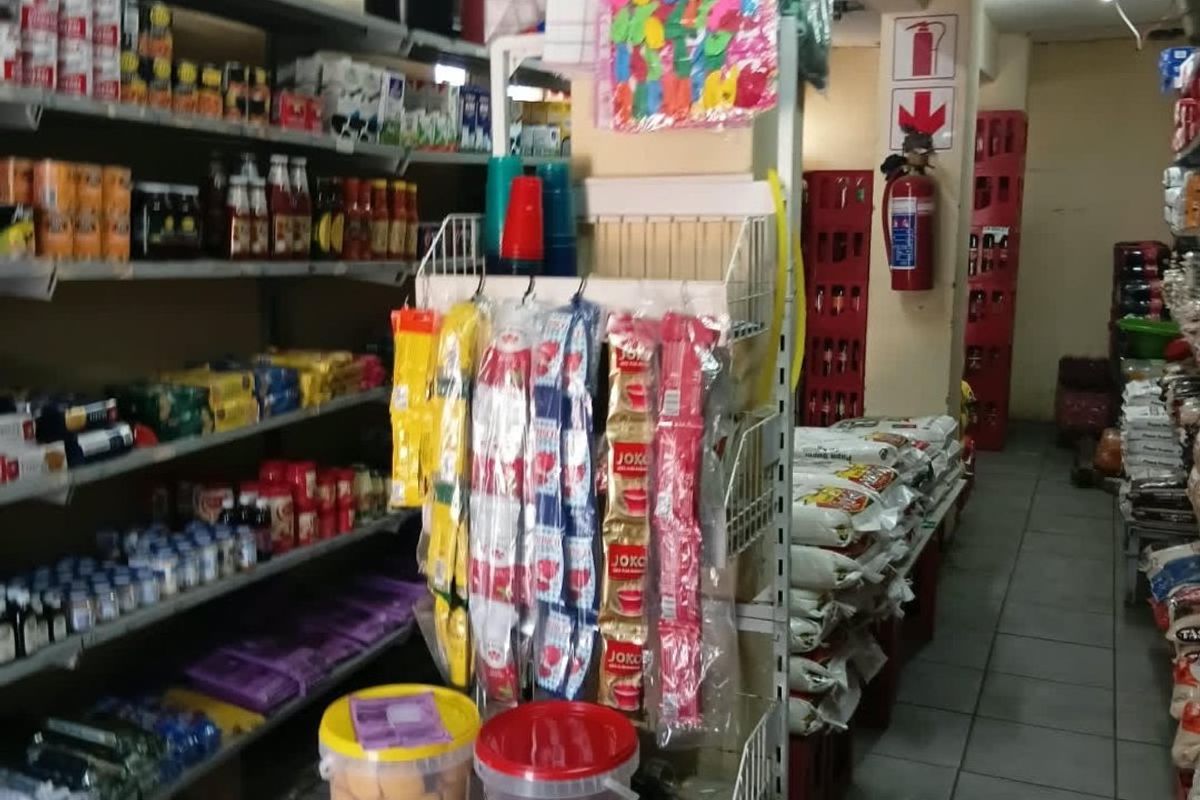 Interior view of a commercial retail space featuring tiled flooring, a structural column, and wall-mounted fire safety equipment.