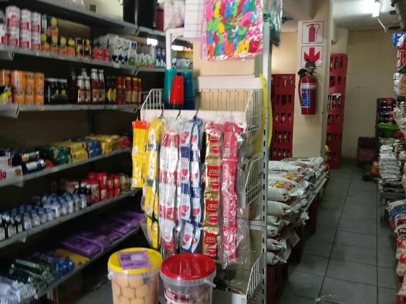 Interior view of a commercial retail space featuring tiled flooring, a structural column, and wall-mounted fire safety equipment.