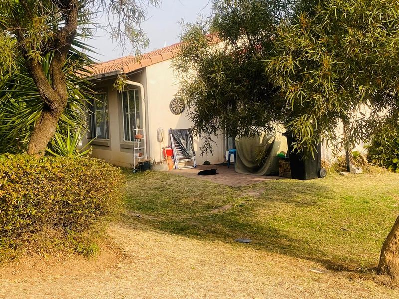 Rear view of the property featuring a paved patio area, established garden, and plastered exterior walls with tiled roofing.