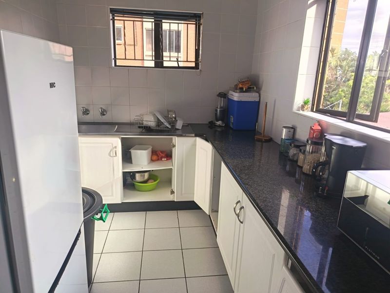 A functional kitchen featuring granite countertops, tiled backsplash, and white cabinetry. The space requires minor repairs to cabinetry and cosmetic updates.